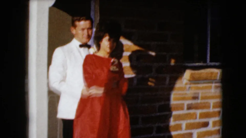 A 1968 Clarksdale, Arizona frame shows the formally dressed couple posing closely against a brick porch wall.