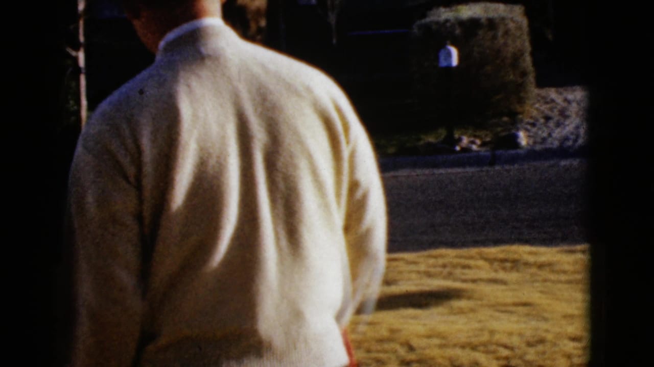 1968 Clarksdale, Arizona home-movie frame showing a man from behind near a residential lawn and street.