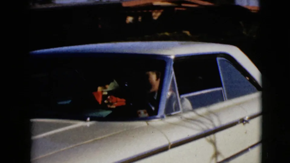 The white sedan is shown closer from the front side, with at least one adult visible inside through the window.