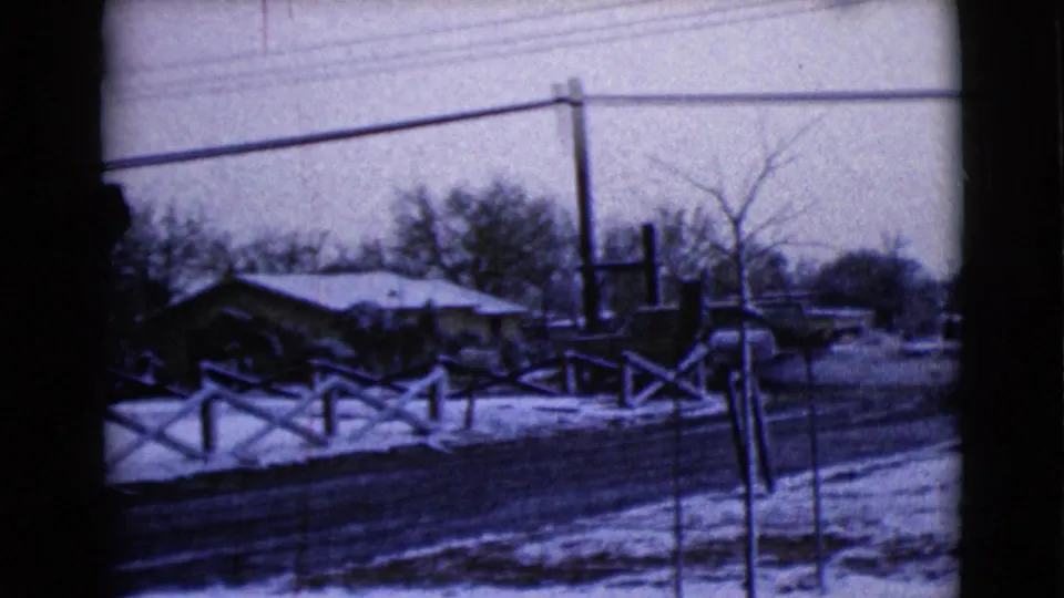 1968 Clarksdale, Arizona home-movie view of snowy residential frontage with fencing, utility poles, bare trees, and low houses.