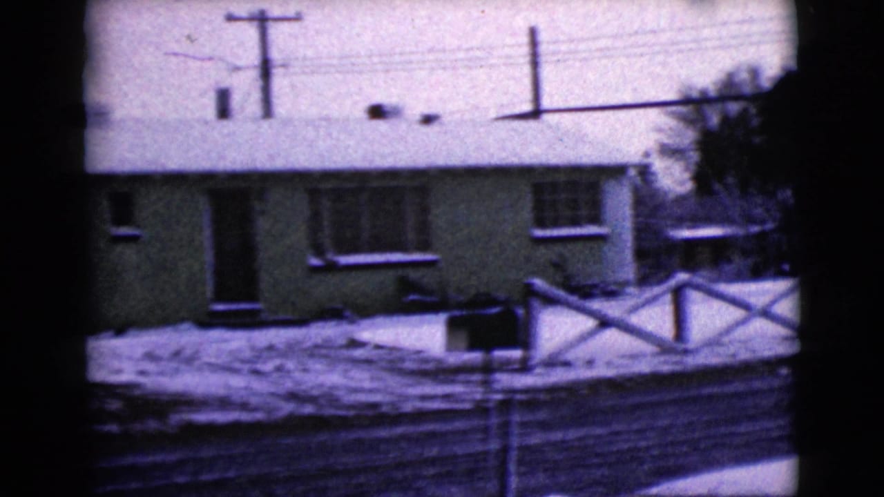 Snow-covered residential frontage in Clarksdale, Arizona, showing a modest 1960s-era home, fence, road, and utility lines.