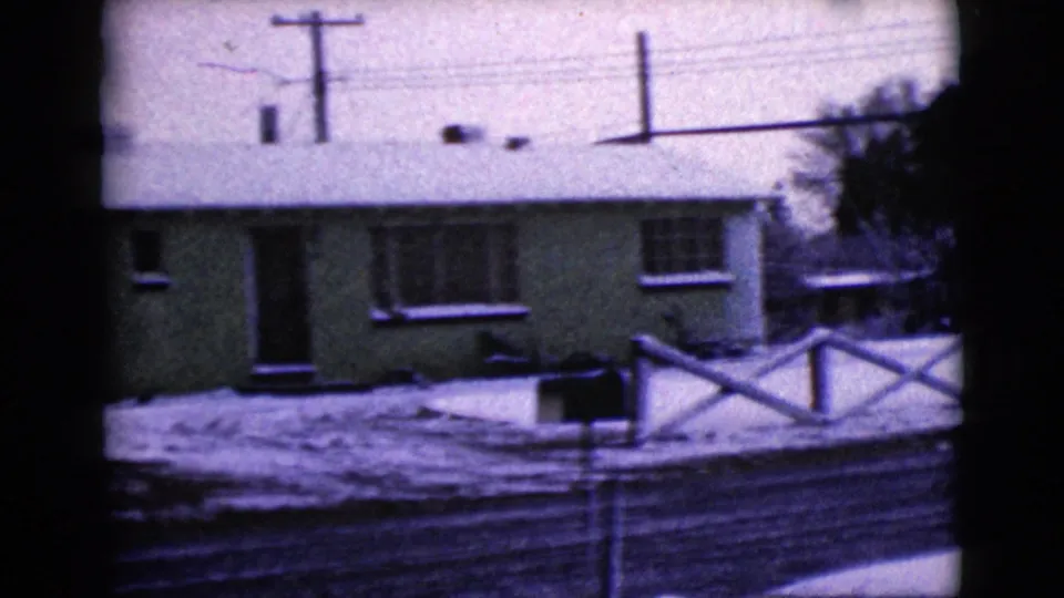 Snow-covered residential frontage in Clarksdale, Arizona, showing a modest 1960s-era home, fence, road, and utility lines.