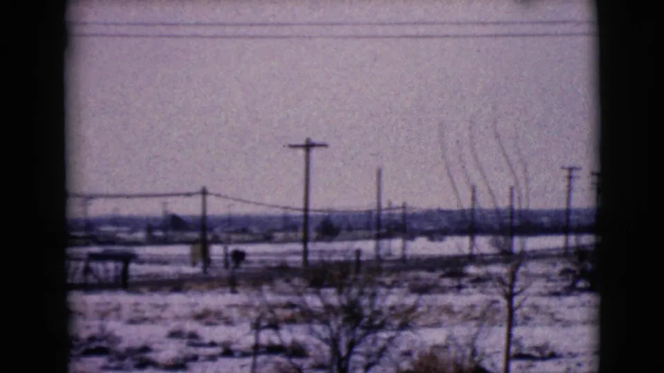 Snowy Clarksdale, Arizona roadside view with utility poles, bare trees, overhead wires, and a distant low horizon.