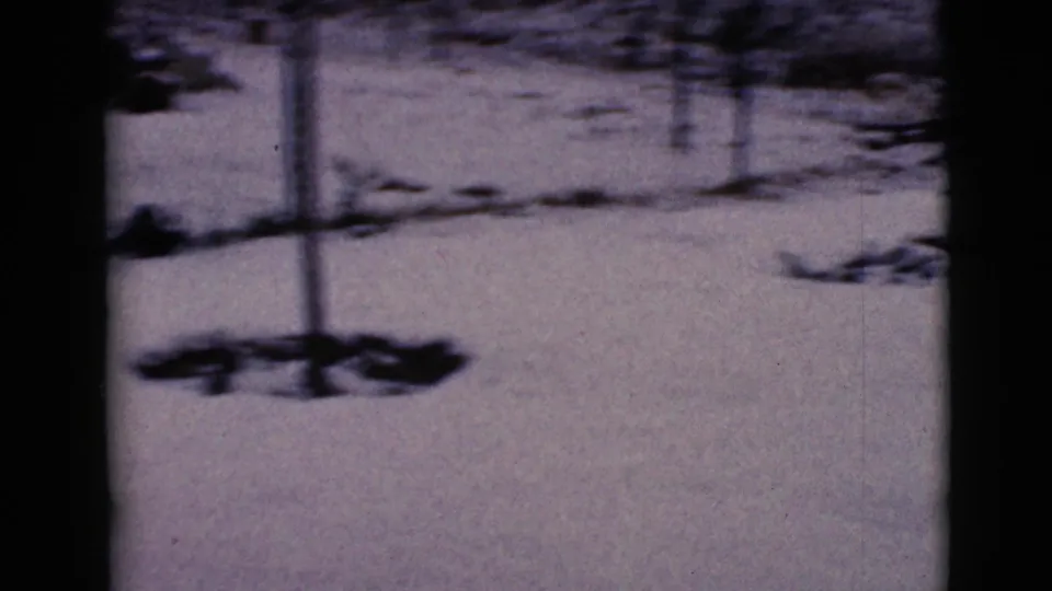 1968 8mm frame from Arizona showing snow-covered ground with dark shadows and a soft, handheld home-movie look.