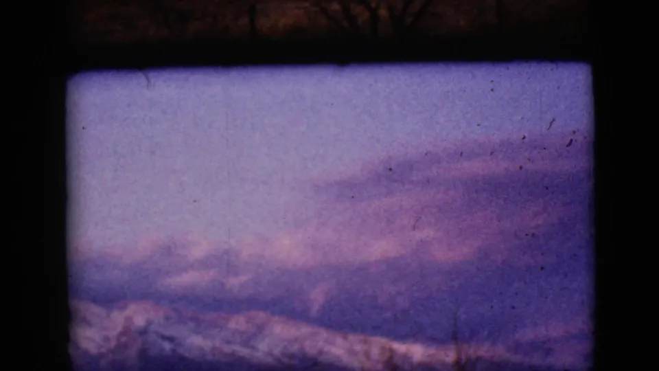 A faded 8mm frame shows a snow-streaked mountain ridge near Clarksdale, Arizona, under a muted dusk sky.