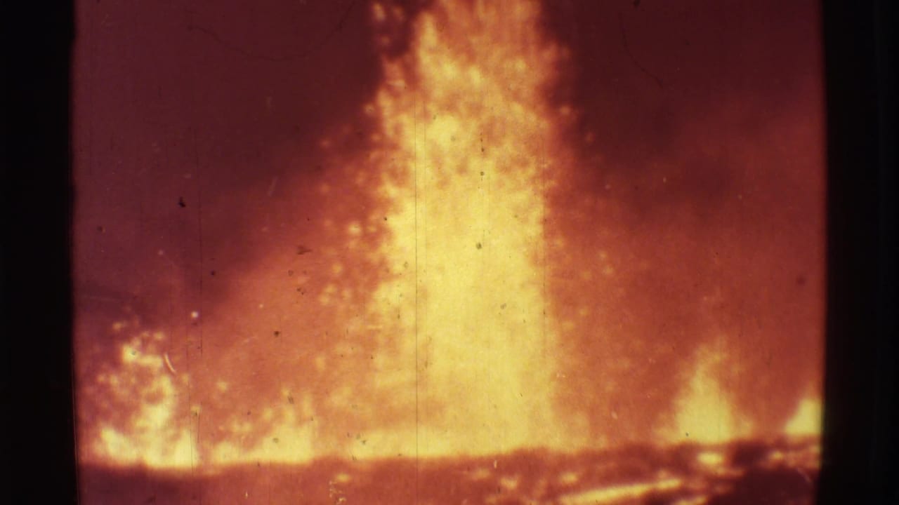 Tall lava fountain rising from a glowing line of fire at night.
