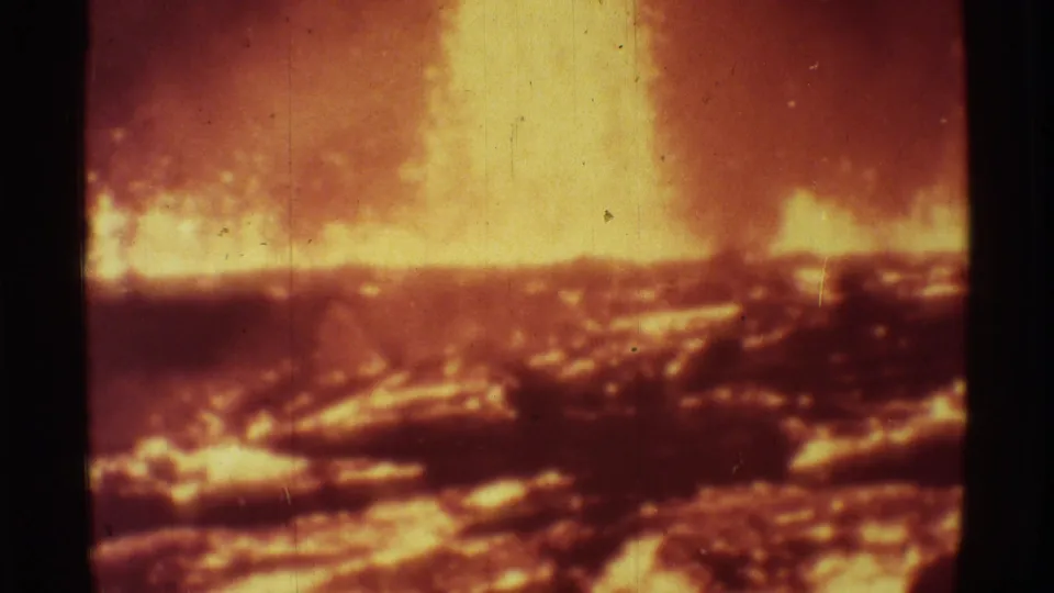 1971 8mm frame from Mauna Ulu showing bright lava glow blooming across dark, crusted volcanic terrain.