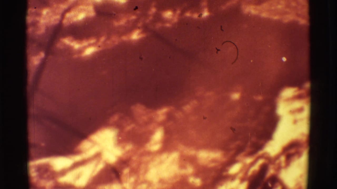 Bright molten lava glows beneath dark volcanic crust in a soft, scratched film frame.