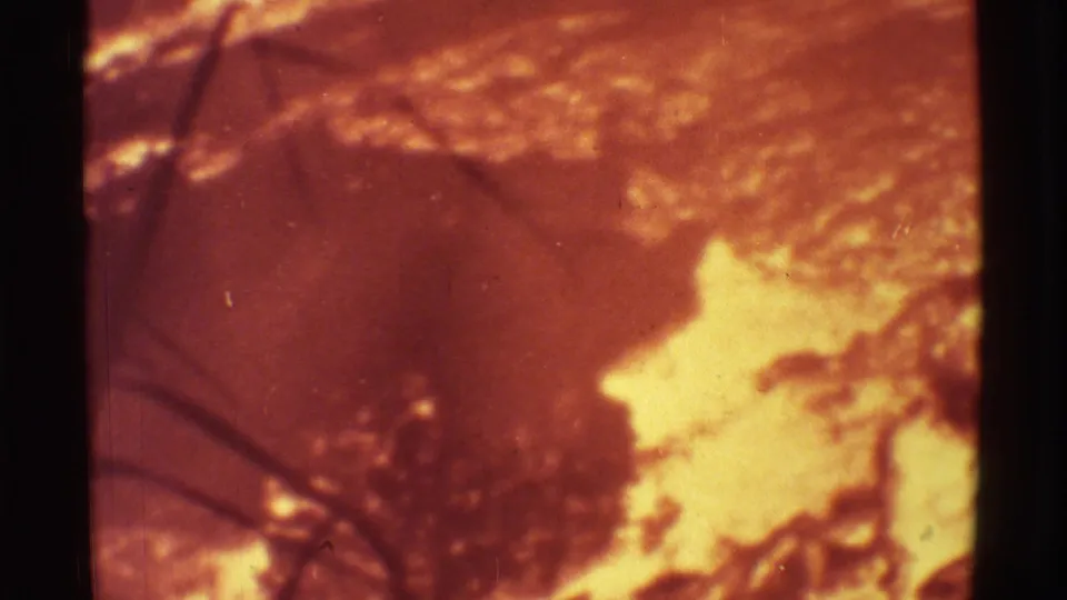 1971 Mauna Ulu, Hawaii 8mm frame showing a bright lava flow area, orange volcanic ground, and dark scrub silhouettes.