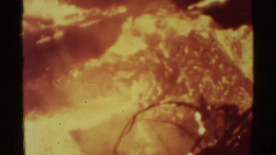 1971 Mauna Ulu 8mm frame with orange lava glow, soft branches, dark edges, grain, and scratches.