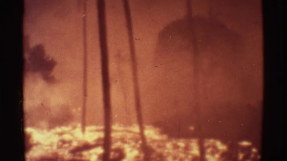 1971 Mauna Ulu home-movie frame showing silhouetted palms, smoke, and bright molten lava along the lower edge.