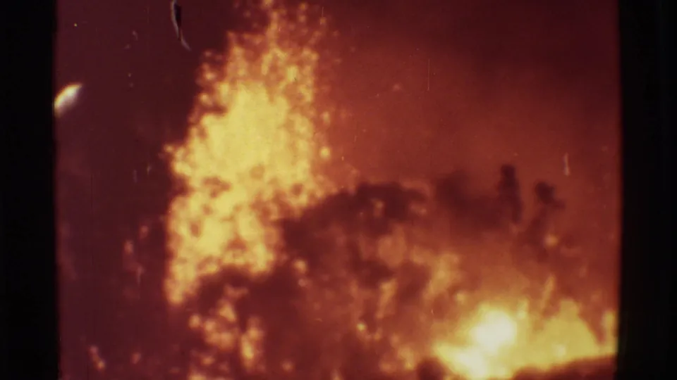 1971 Mauna Ulu 8mm frame showing bright lava shooting upward through smoke, with dark foreground vegetation and visible film wear.