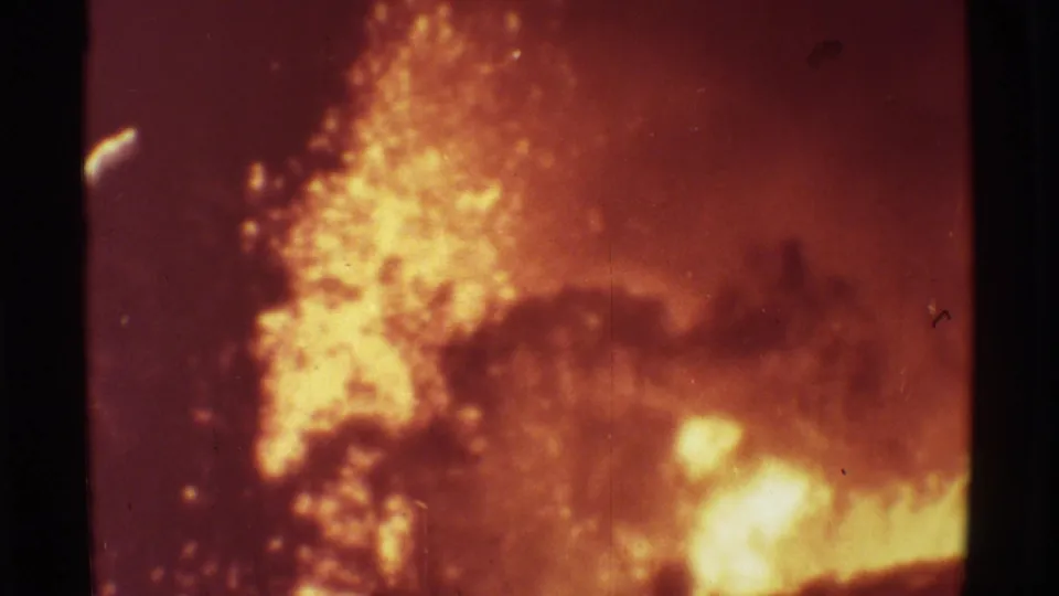 1971 Mauna Ulu 8mm frame showing an intense lava fountain, low glowing fire, smoke, and silhouetted vegetation through grainy film.