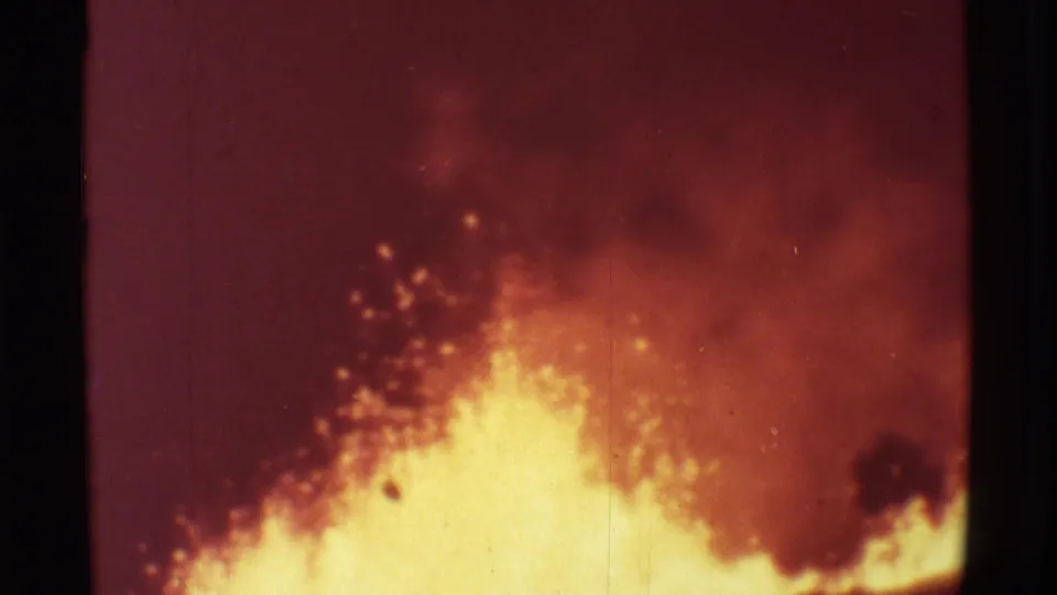 1971 Mauna Ulu 8mm frame with a bright lava burst at the lower edge, sparks rising into smoke, and dark vegetation at right.