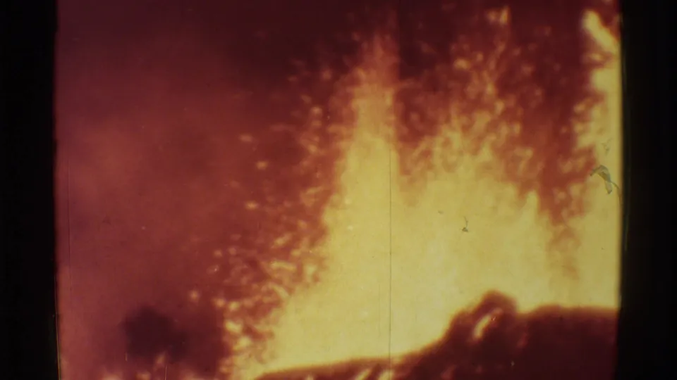 1971 Mauna Ulu 8mm frame showing dense glowing lava spray behind dark rock, with warm color shift and grain.