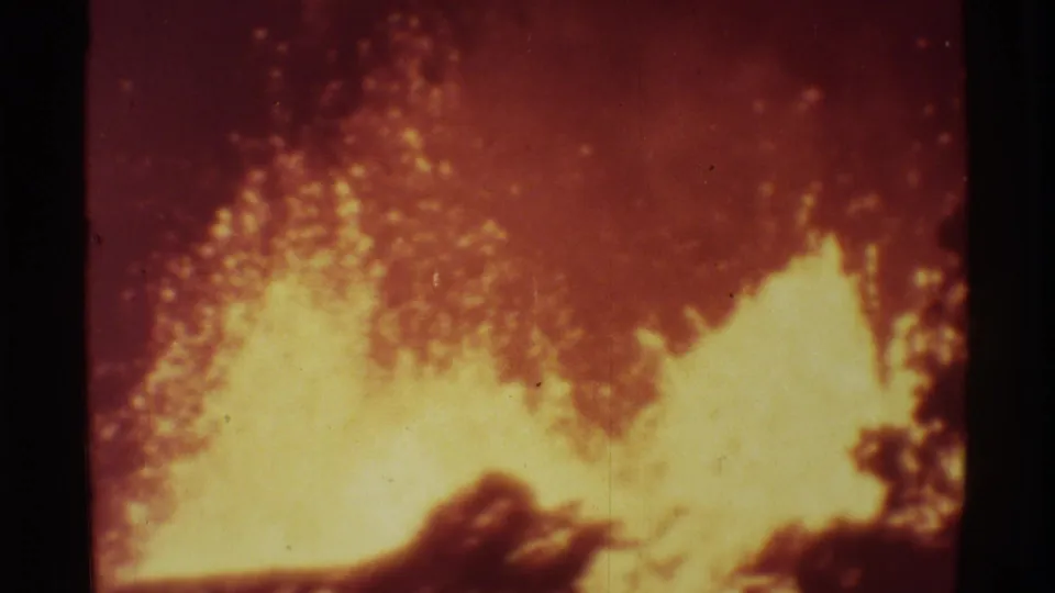 1971 Mauna Ulu 8mm frame showing bright molten lava erupting against a dark red-orange volcanic background.