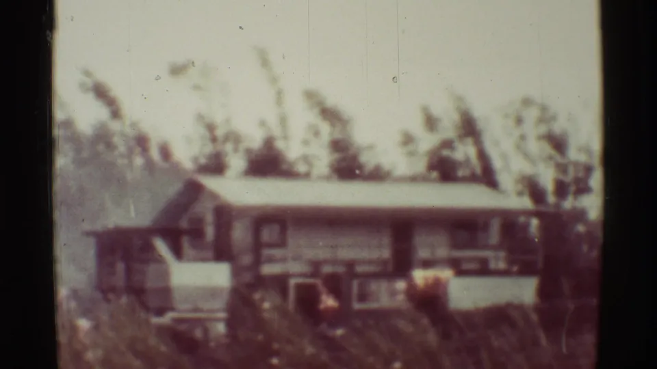 1971 Mauna Ulu, Hawaii 8mm frame showing a low house partly obscured by trees before the visible fire intensifies.