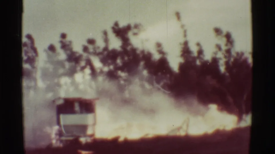 By the final frame, smoke and flame dominate the wooded scene, with the structure mostly obscured in the Mauna Ulu 1971 home-movie footage.