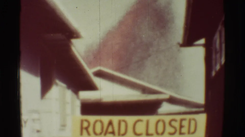 Vintage 8mm view of the ROAD CLOSED warning as a dark volcanic plume rises in the background at Mauna Ulu.