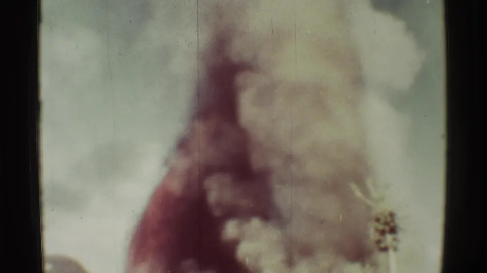 1971 Mauna Ulu, Hawaii frame showing billowing smoke and haze, with a small foreground seed head near the right edge.