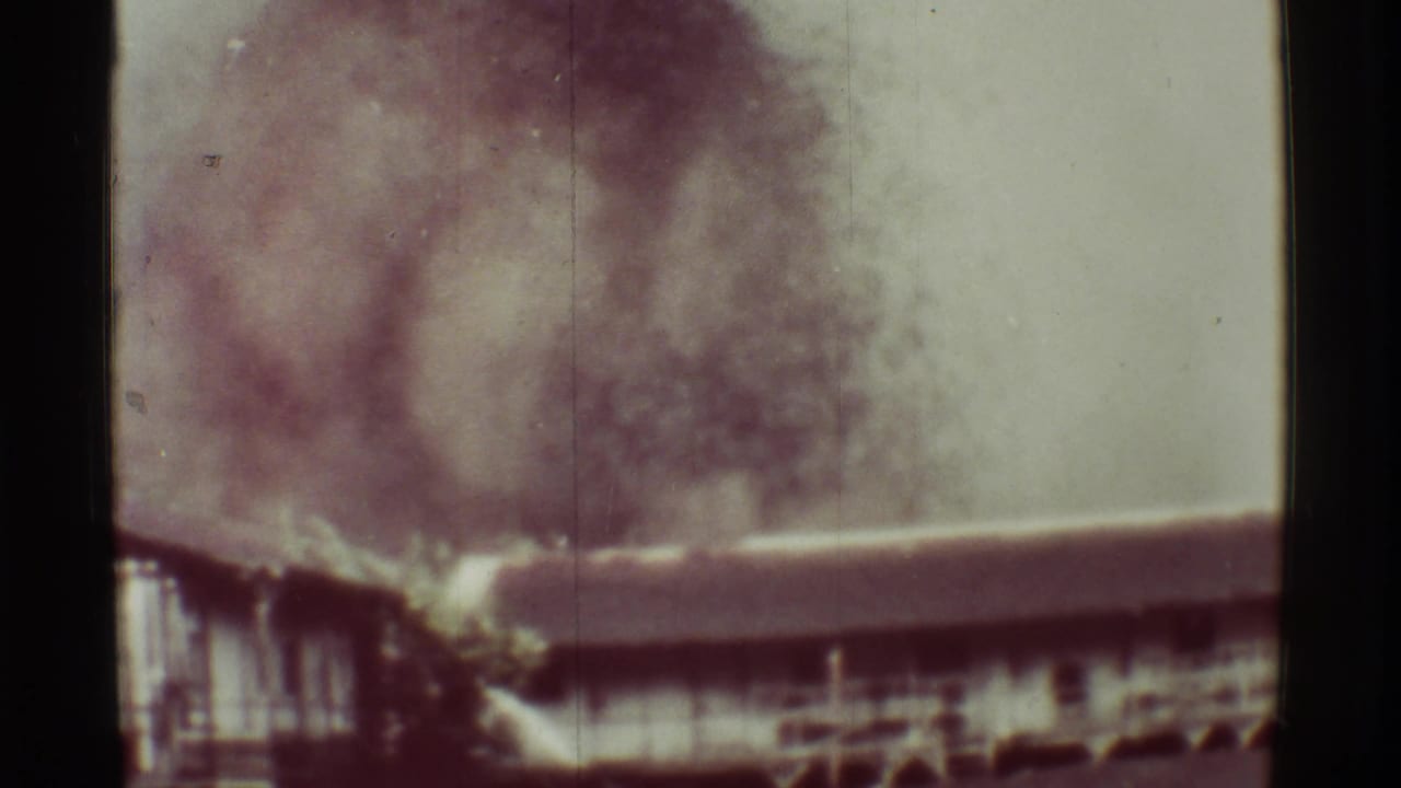 1971 Mauna Ulu, Hawaii 8mm frame showing a low structure with dark smoke or dust rising in the background.