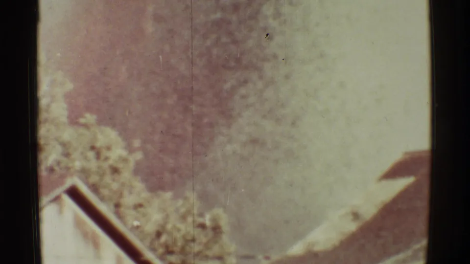 1971 Mauna Ulu 8mm frame with vegetation, a roofline, and pale volcanic haze softened by film exposure.