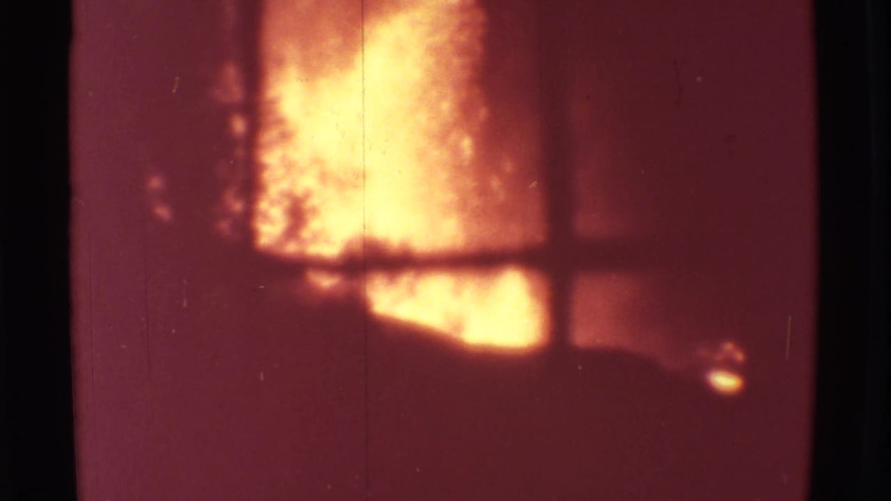 Orange volcanic plume glows behind a window frame with dark borders.
