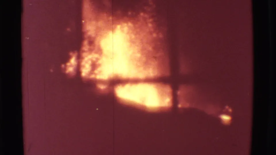 The 1971 Mauna Ulu lava flare appears soft and bright behind a window grid, with reddish 8mm color and visible grain.