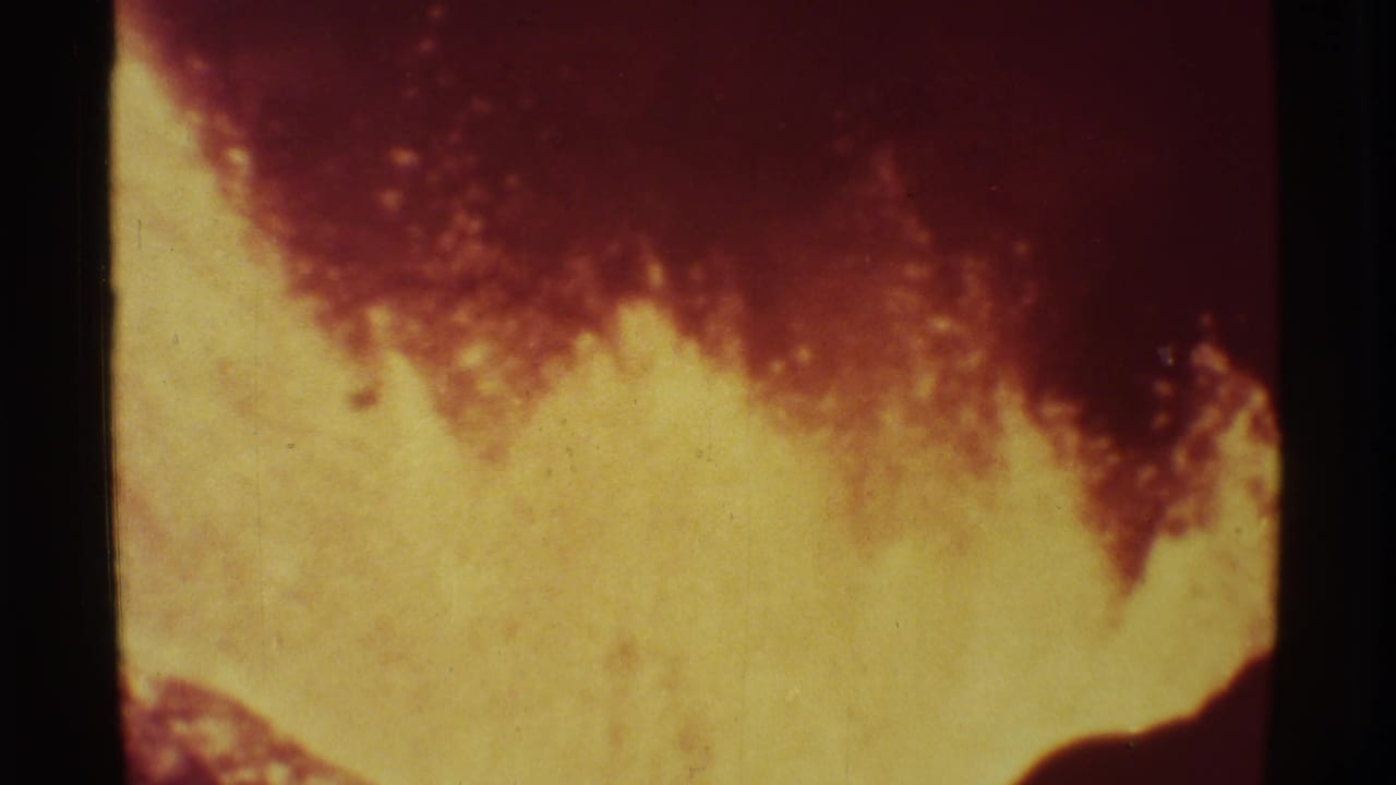 Bright yellow lava glow rises beneath a dark red upper plume with black film borders.