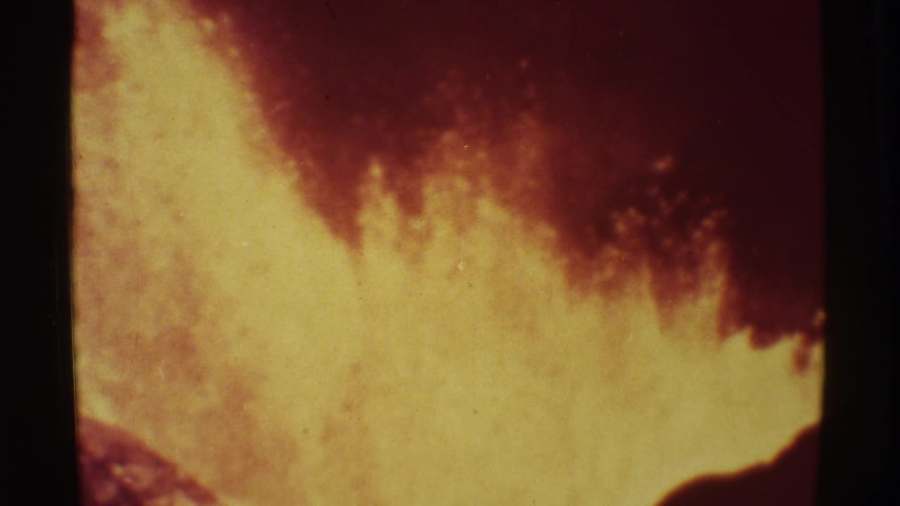 Yellow volcanic glow and red smoke fill the frame, separated by a dark vertical film bar.