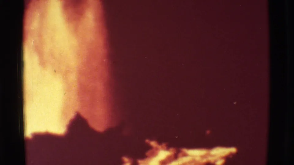 1971 Mauna Ulu 8mm frame showing a tall yellow-orange lava flare near dark volcanic silhouettes and a red glowing background.