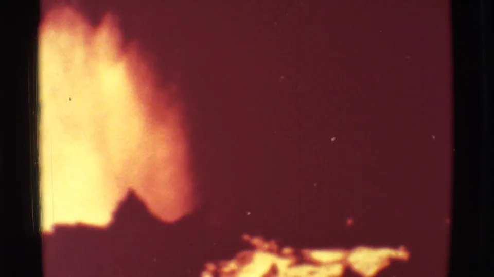1971 Mauna Ulu 8mm frame with a yellow lava flare at left, dark volcanic silhouettes below, and a red glowing field to the right.
