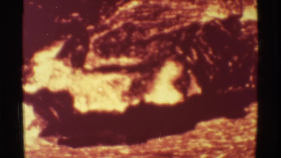 1971 Mauna Ulu, Hawaii 8mm frame showing a dark lava crust surrounded by bright molten yellow-orange glow on rough terrain.