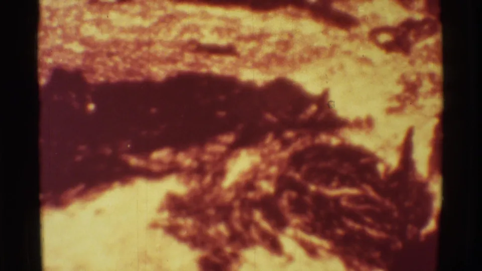 1971 Mauna Ulu 8mm frame showing molten lava glowing through dark crusted flow, with heavy grain and warm red-orange exposure.