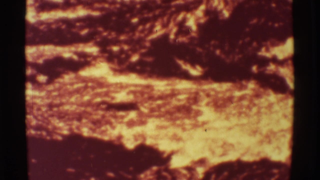 1971 Mauna Ulu 8mm frame showing incandescent lava beneath a dark crusted surface, rendered in saturated red-orange film color.