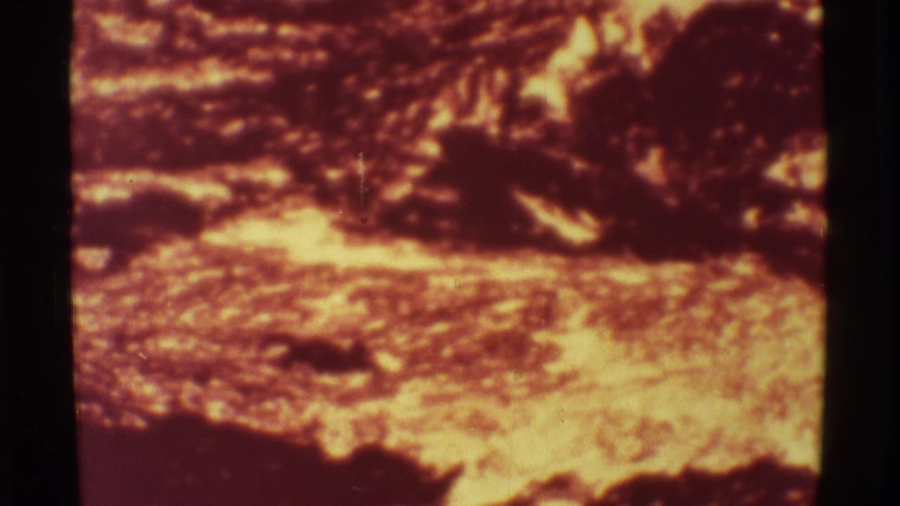 Glowing lava and dark volcanic crust in a warm, grainy 8mm frame.
