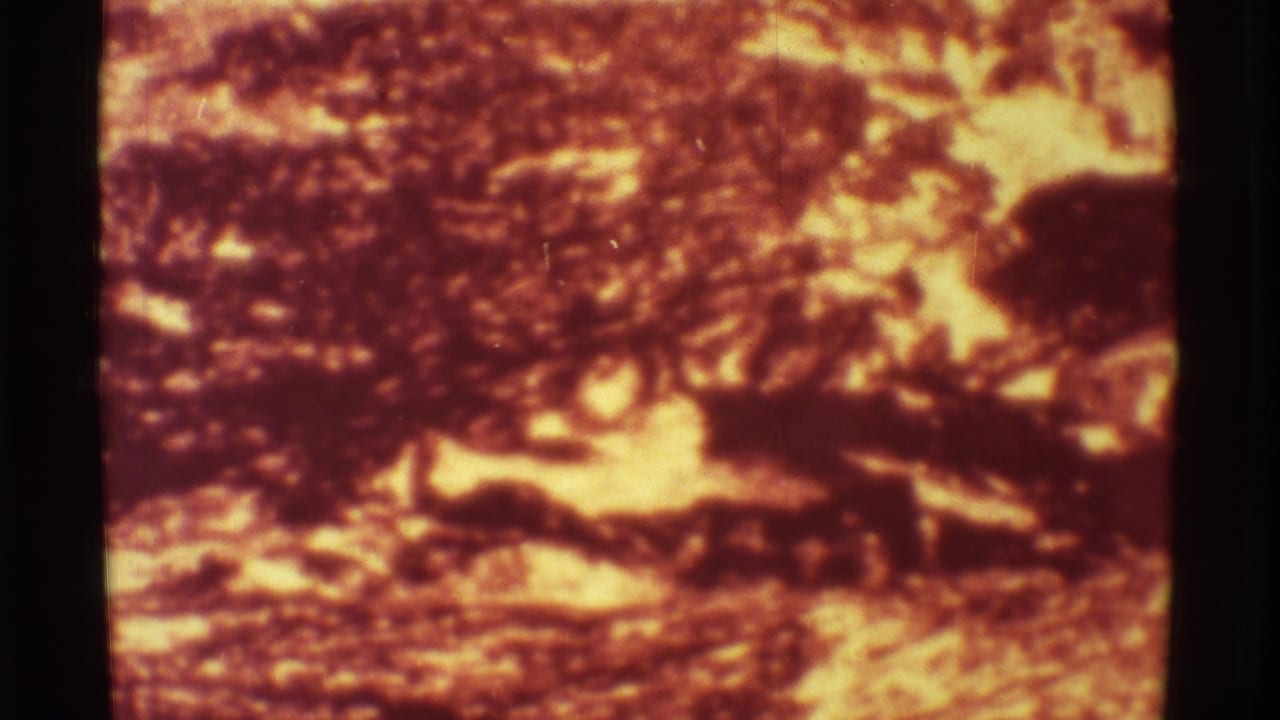 Mauna Ulu 8mm frame showing glowing lava surface, dark crusted shapes, and visible film borders.