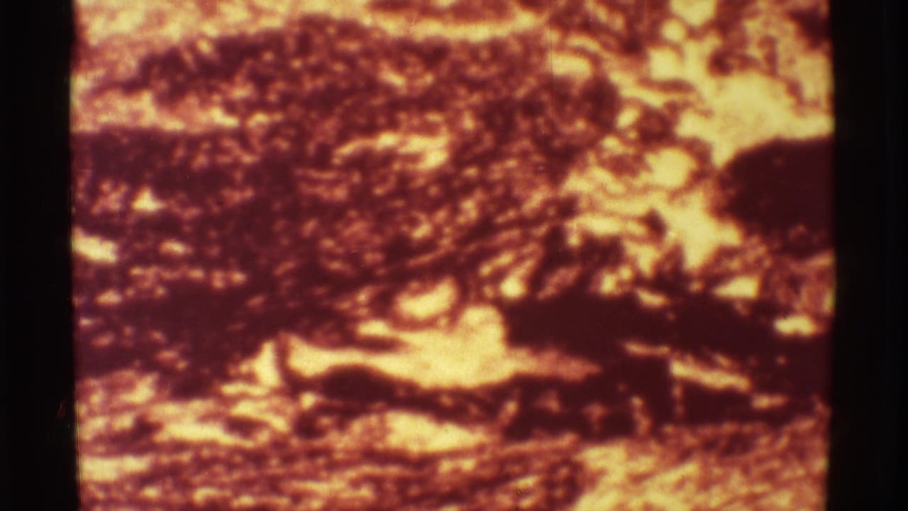 Blurry red-orange volcanic fire and dark landscape seen through 8mm film framing.