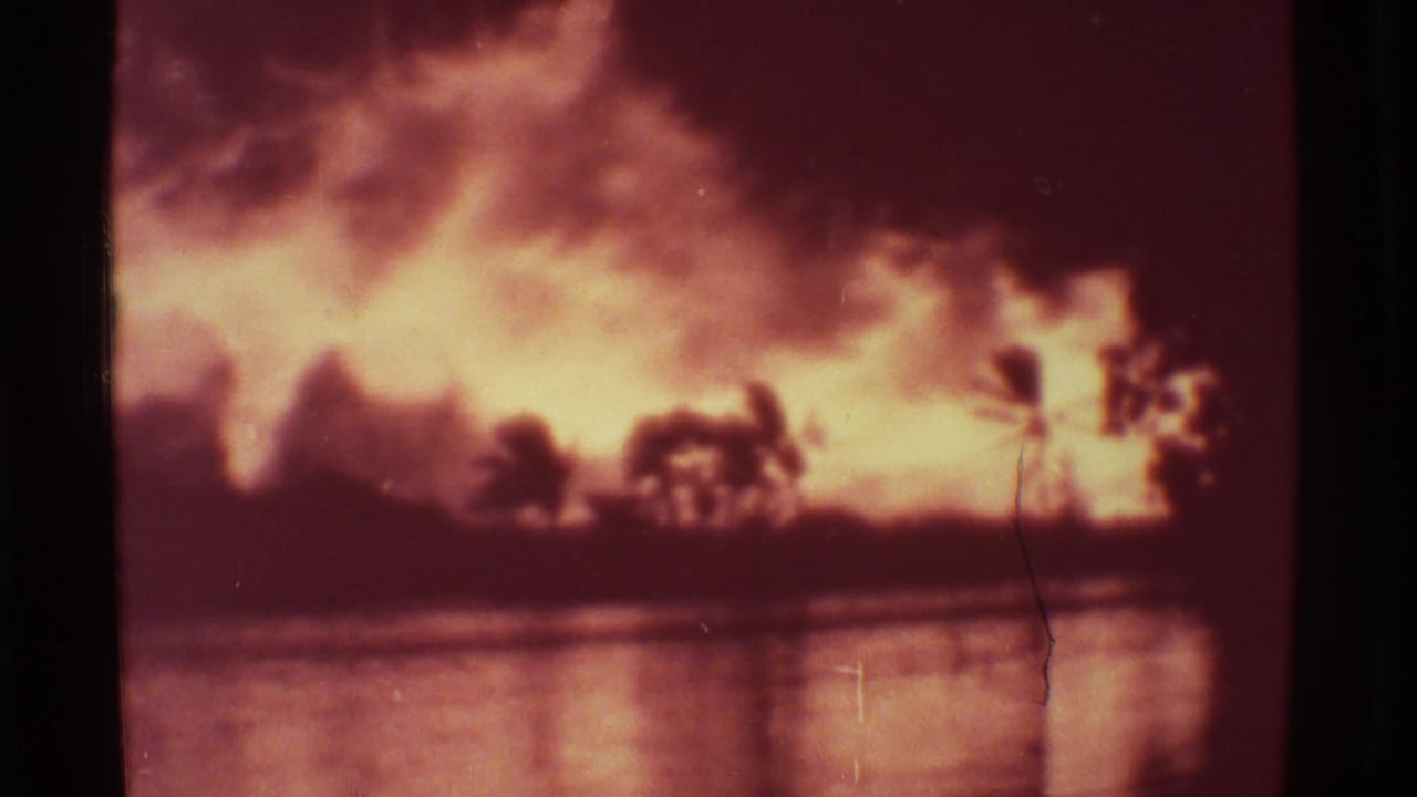 1971 Mauna Ulu home-movie frame with bright volcanic glow, smoke, silhouetted palms, and reflected light on water.