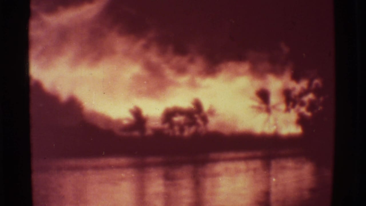 Mauna Ulu 1971 8mm frame showing orange volcanic fire, smoke, palm silhouettes, and shimmering reflected light.