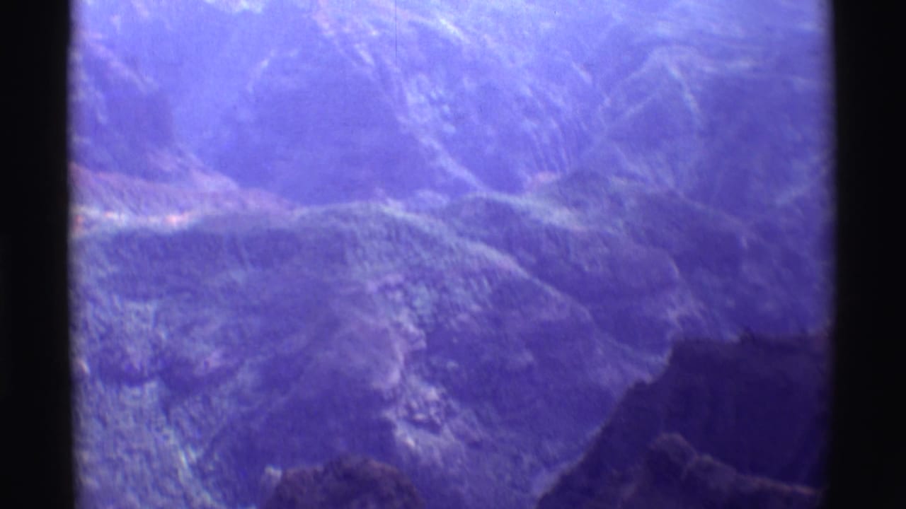 1971 8mm Hawaii landscape frame showing blue-toned valleys, ridges, and a dark foreground slope.