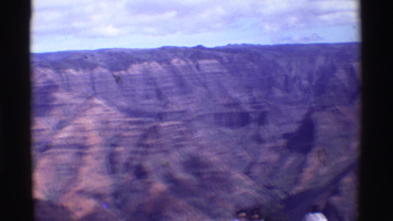 Soft 8mm view across layered canyon walls under a cloudy sky.