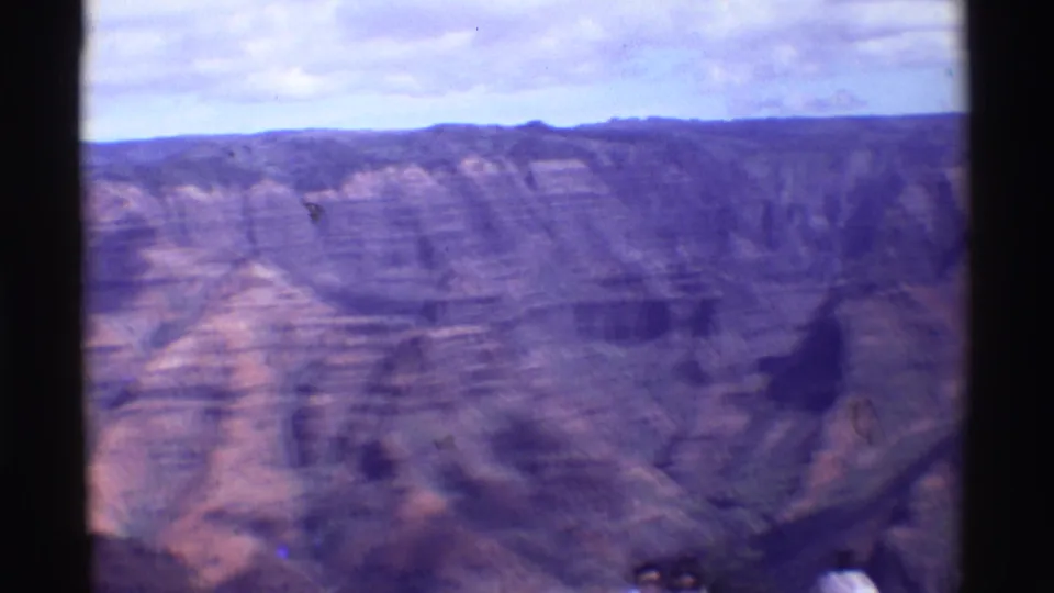 1971 8mm travel frame of a broad, layered canyon landscape in the Mauna Ulu, Hawaii metadata location.