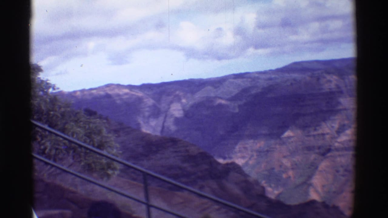 Canyon landscape seen from a lookout with a metal railing and cloudy sky.