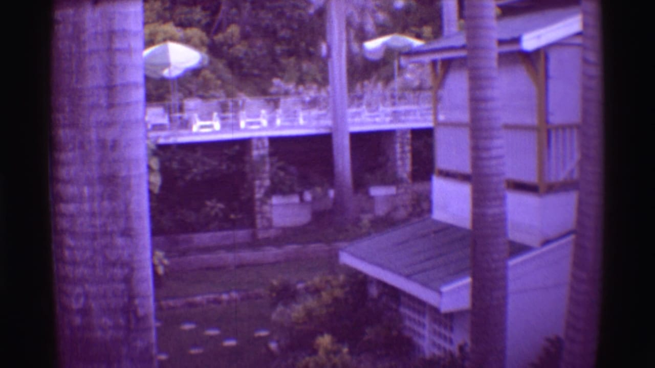 1971 Mauna Ulu resort exterior showing a building with railings and awning beside palms, umbrellas, and garden paths.
