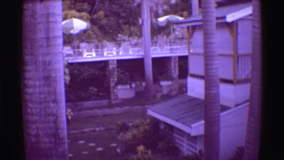 1971 Mauna Ulu resort exterior showing a building with railings and awning beside palms, umbrellas, and garden paths.