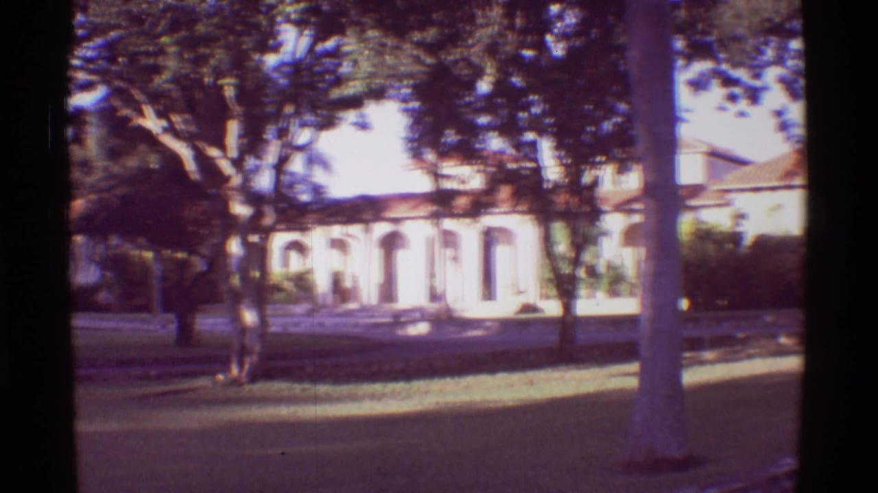 1971 Mauna Ulu, Hawaii home-movie view of a resort facade with arches, trees, lawn, and a foreground palm trunk.