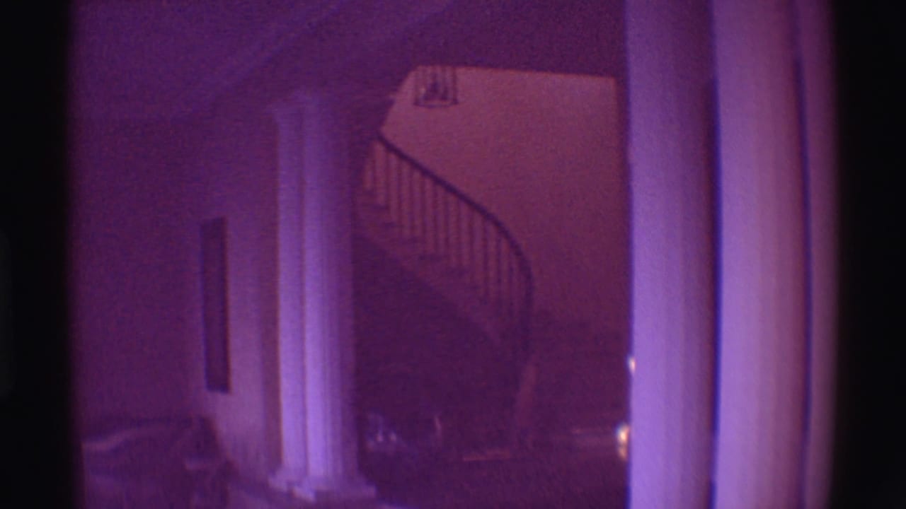 1971 Hawaii estate interior with white columns, a shadowed hallway, and a curved staircase under a purple film cast.