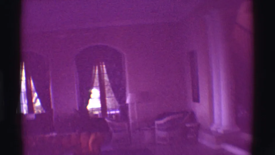 1971 Hawaii interior frame showing a living room with arched windows, curtains, chairs, columns, and a pronounced purple color cast.