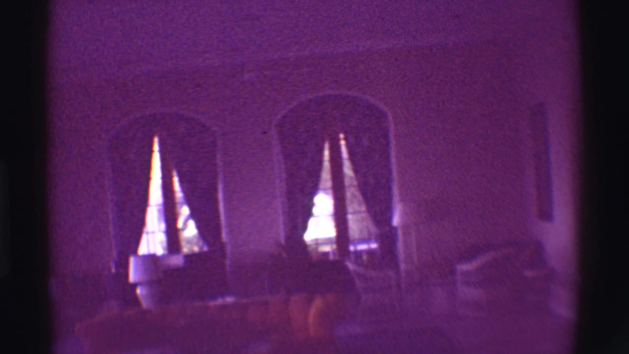 Dim purple-tinted interior with arched windows, curtains and upholstered seating.